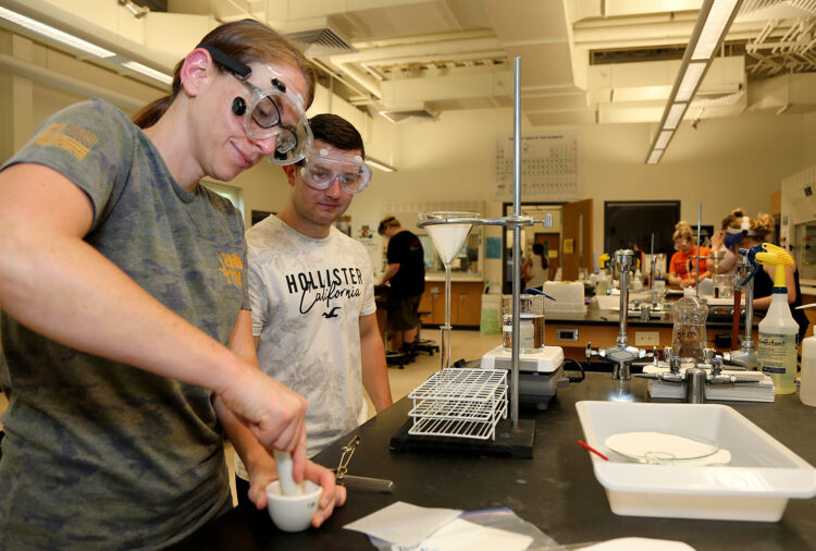 two students in chemistry lab with mortar and pestle