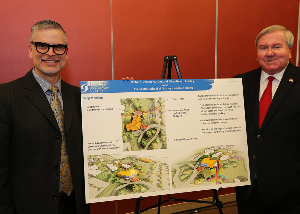two men standing in front of a poster showing plans for bc3's shaffer school of nursing and allied health and victor k phillips building