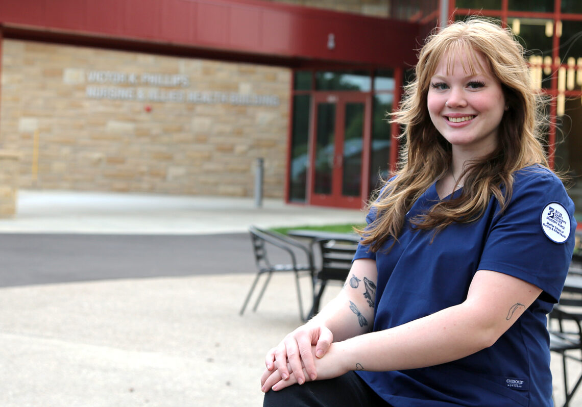 young woman smiling in nursing uniform, bc3 student mya sloamers